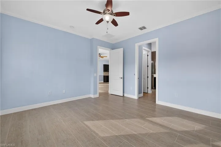Primary bedroom with crown molding, tiled floors, and ceiling fan.