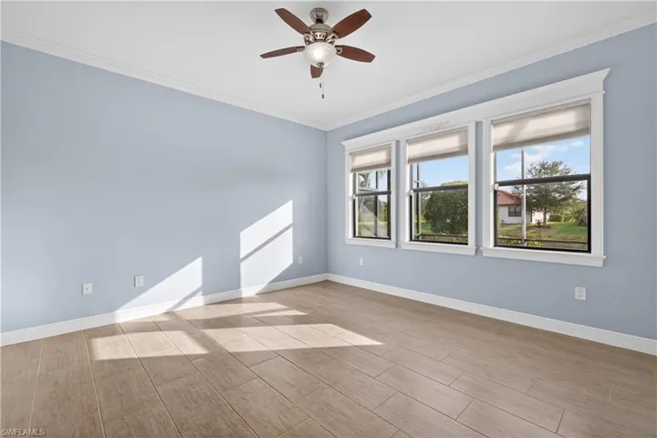 Primary bedroom with crown molding, tiled floors, and ceiling fan.