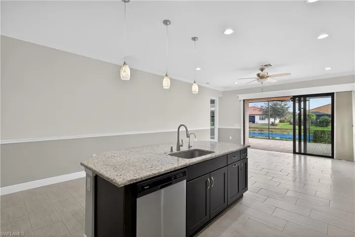 Kitchen with large island, pendant light fixtures, granite counters, tile backsplash, stainless steel appliances, pantry and tranquil water views.