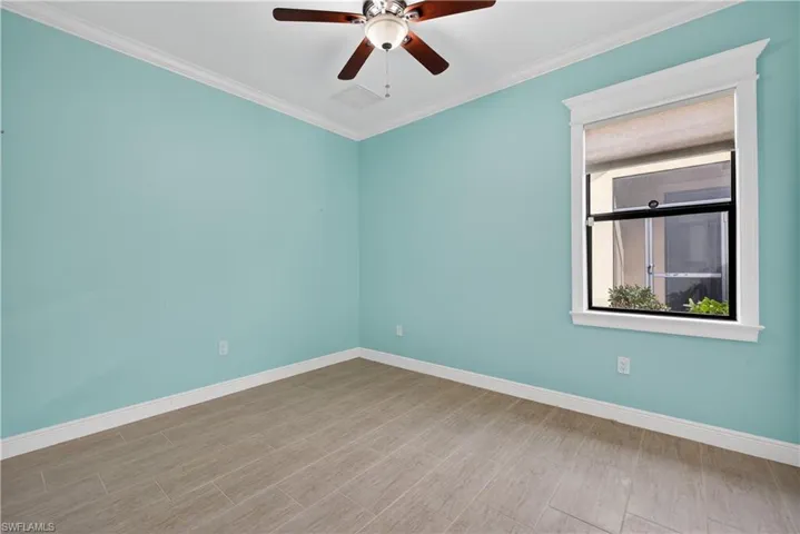 Guest bedroom with tile floors, crown molding and ceiling fan.