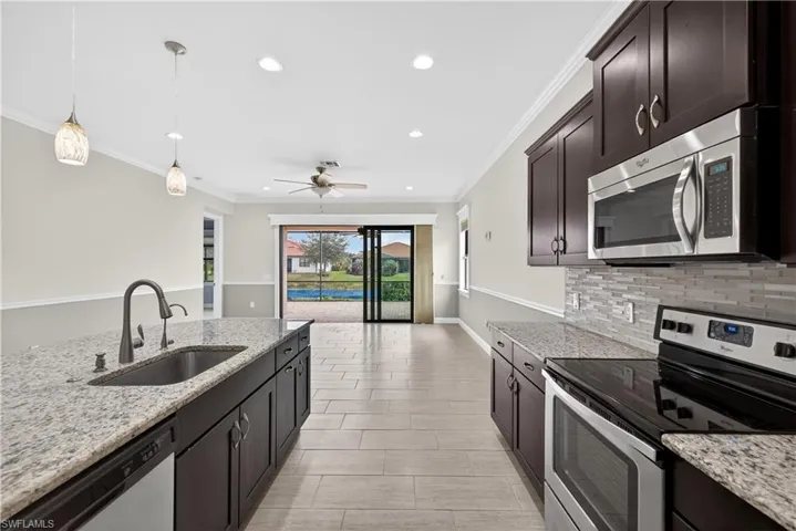 Kitchen with large island, pendant light fixtures, granite counters, tile backsplash, stainless steel appliances, pantry and tranquil water views.