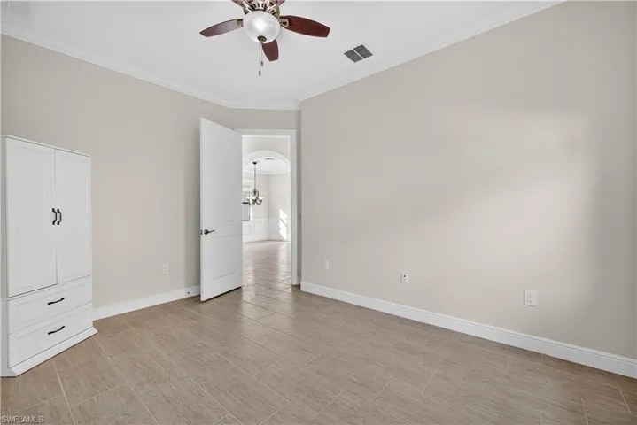 Guest bedroom with tile floors, crown molding and ceiling fan.