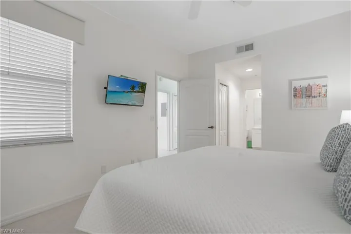 Carpeted bedroom featuring ceiling fan and ensuite bathroom