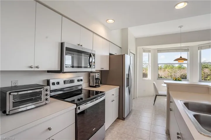 Kitchen featuring stainless steel appliances, sink, pendant lighting, and white cabinets