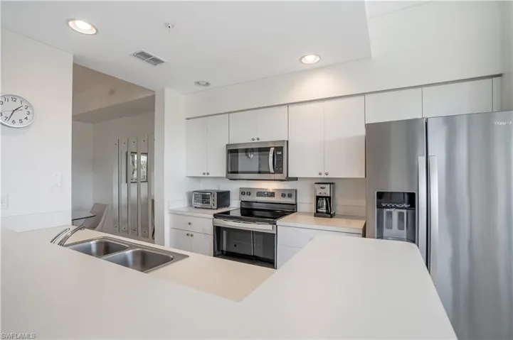 Kitchen with stainless steel appliances, white cabinetry, and sink