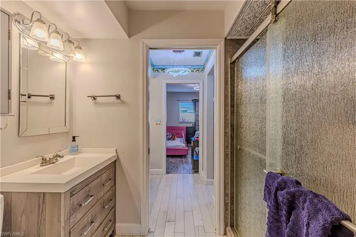 Full bath with vanity, wood finished floors, baseboards, a stall shower, and connected bathroom
