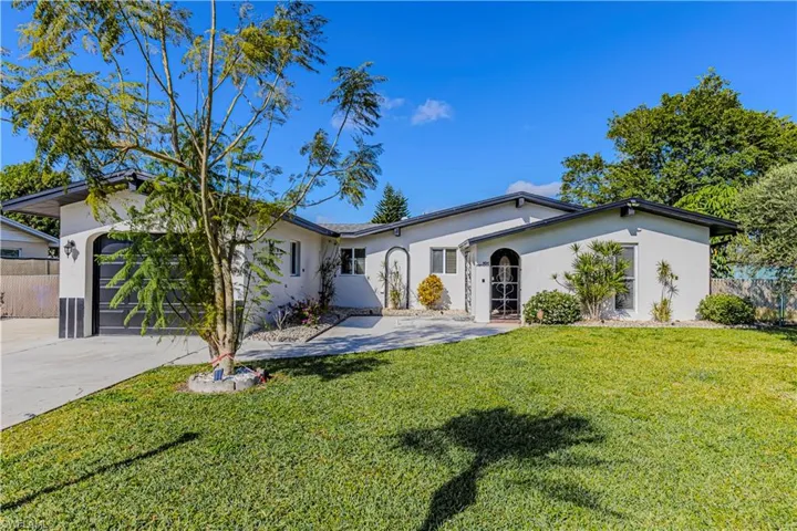 Ranch-style home featuring stucco siding, fence, concrete driveway, a front yard, and a garage