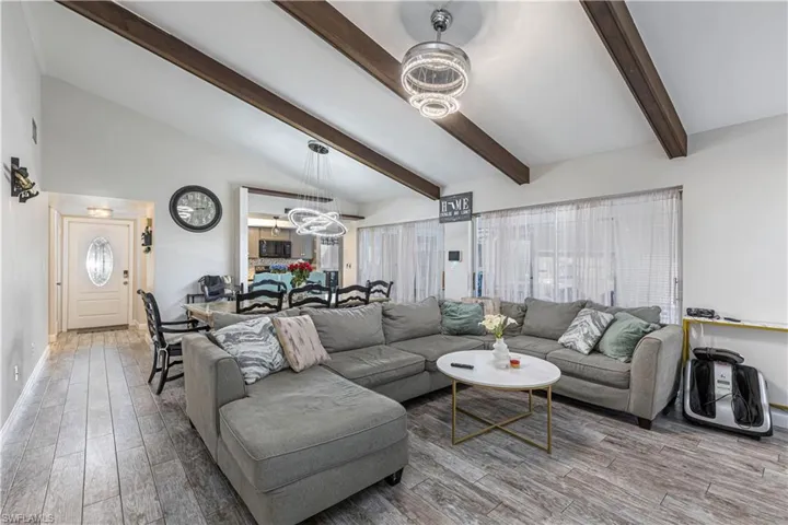 Living room featuring an inviting chandelier, vaulted ceiling with beams, and wood finished floors