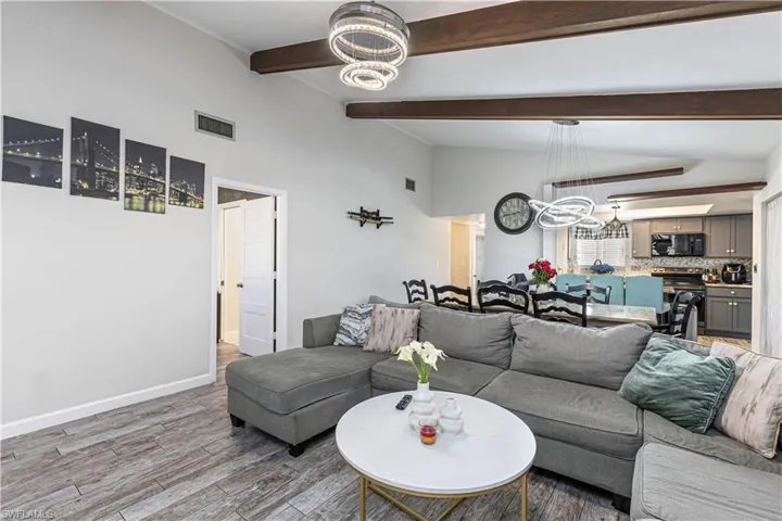 Living room featuring visible vents, wood finished floors, baseboards, and a chandelier