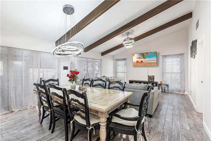 Dining area with a healthy amount of sunlight, lofted ceiling with beams, and wood finished floors