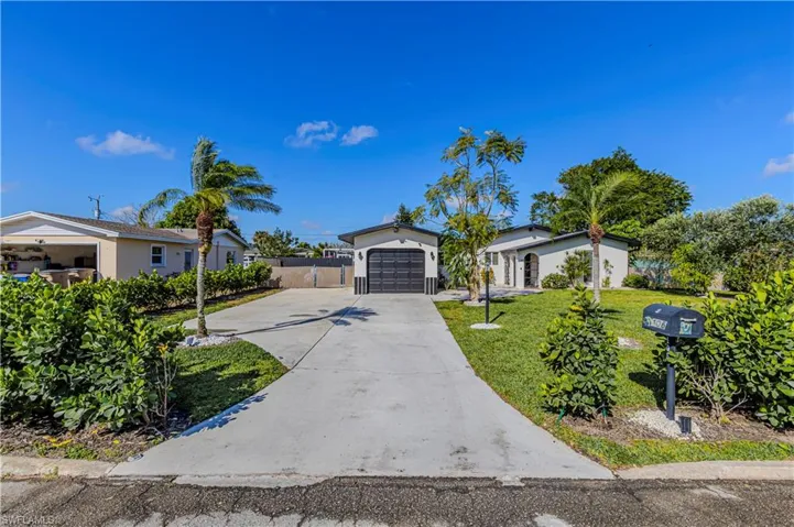 Single story home with a garage, concrete driveway, a front yard, and fence