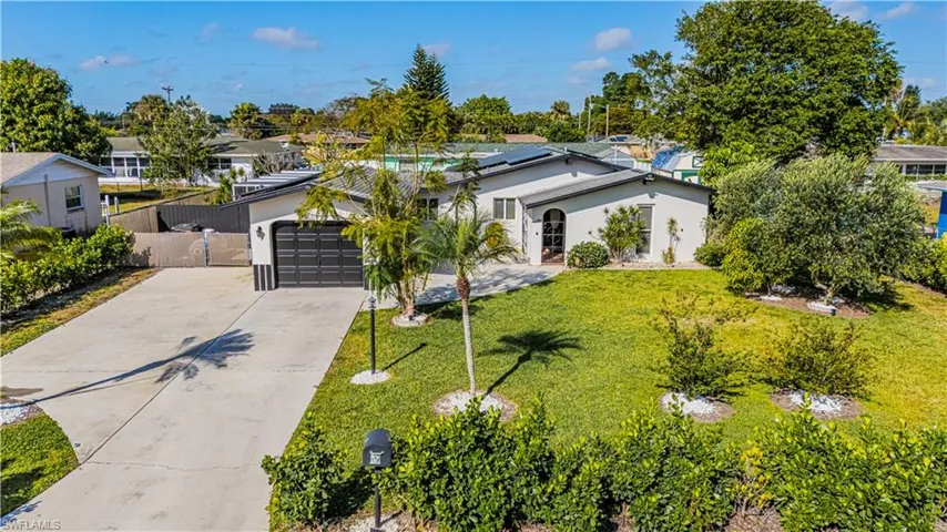 View of front of property featuring stucco siding, fence, concrete driveway, a front yard, and an attached garage