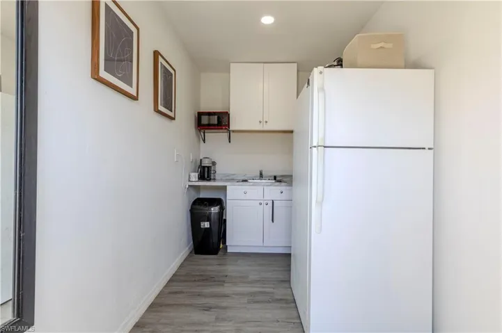 Kitchen with white cabinetry, freestanding refrigerator, light wood finished floors, baseboards, and light countertops