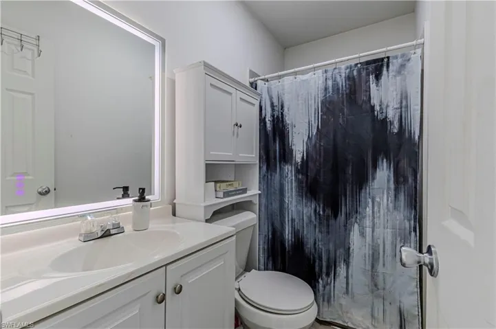 Full bathroom featuring a shower with shower curtain, toilet, and vanity
