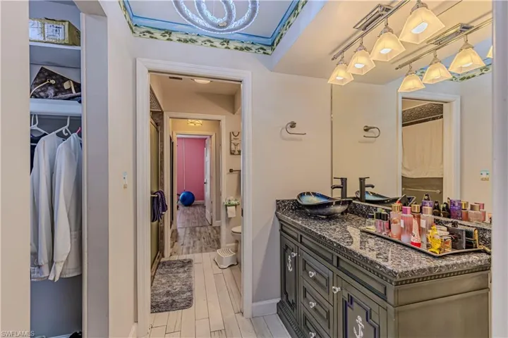 Full bathroom with visible vents, a walk in closet, wood finish floors, toilet, and vanity