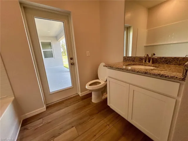 Bathroom featuring wood finished floors, toilet, vanity, and baseboards