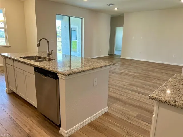 Kitchen with dishwasher, a sink, light wood-style flooring, and healthy amount of natural light