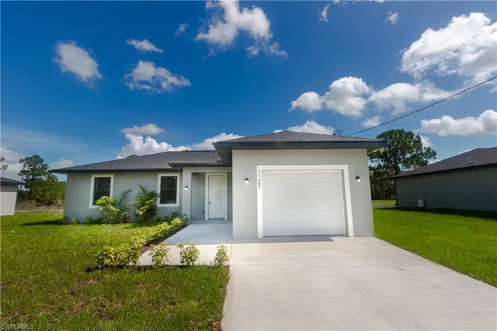Single story home featuring stucco siding, driveway, a garage, and a front lawn