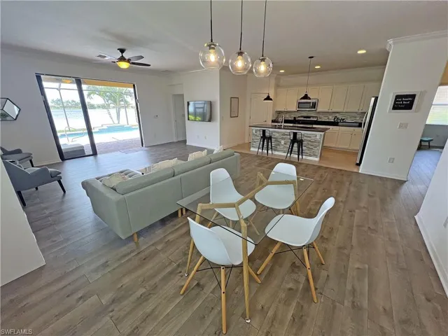 Dining space featuring ceiling fan, crown molding, and wood-style flooring