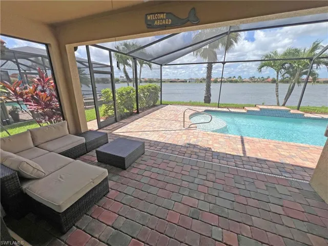 View of swimming pool featuring outdoor lounge area under roof and lake view