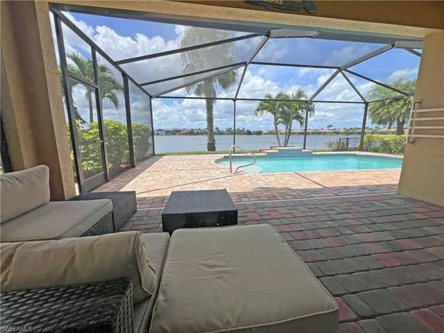 View of swimming pool featuring outdoor lounge area under roof and lake view