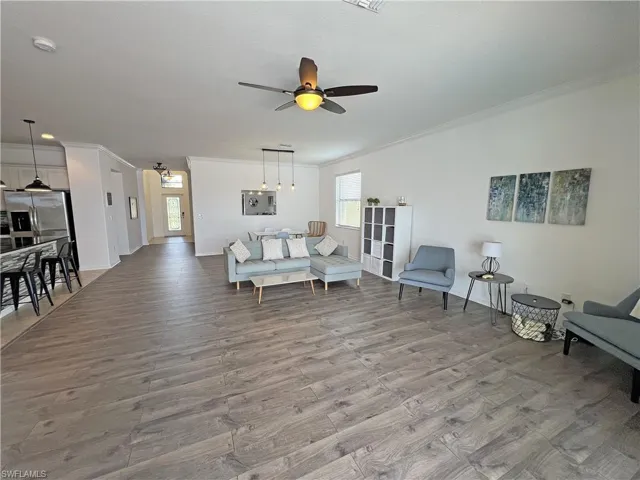 Living room with crown molding, ceiling fan, and wood-style floors