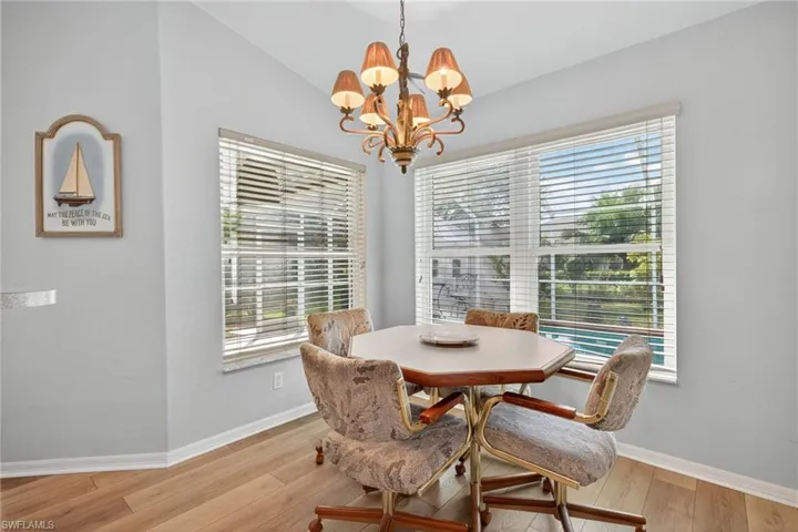 Dining area with light wood-style flooring, a chandelier, and vaulted ceiling