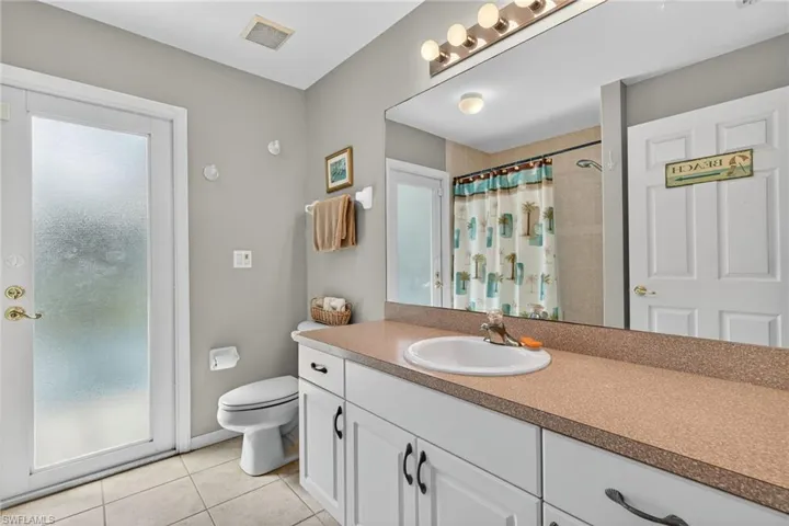 Bathroom with vanity, light tile patterned floors, and curtained shower