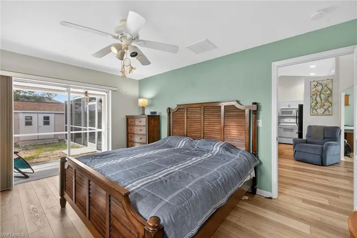Bedroom with light wood-style flooring, access to exterior, a ceiling fan, and black refrigerator
