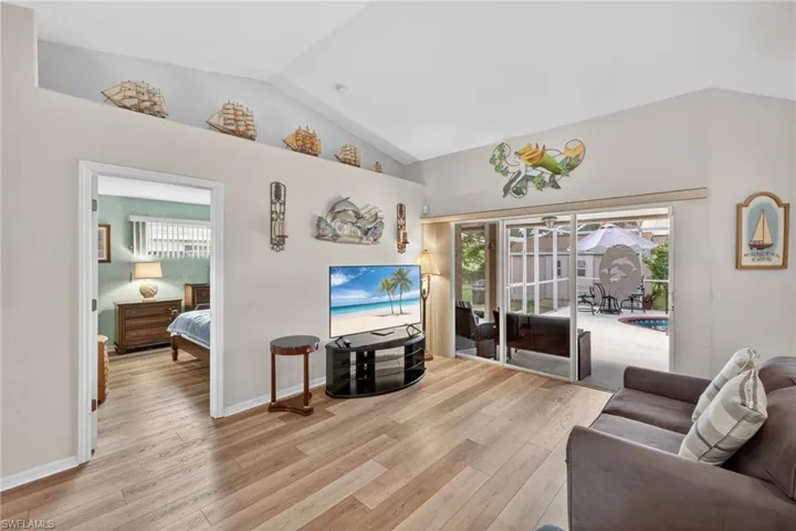 Living area with vaulted ceiling, light wood-style floors, and plenty of natural light