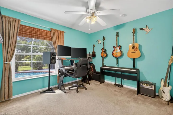 Carpeted office with baseboards and a ceiling fan