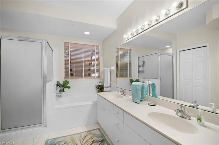 Full bath featuring a shower stall, double vanity, a closet, a bath, and recessed lighting