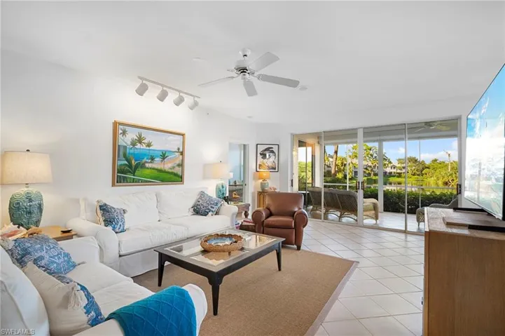 Living room featuring light tile patterned floors, ceiling fan, and track lighting
