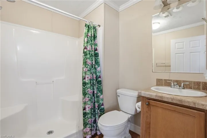 Full bath with vanity, a shower stall, and ornamental molding