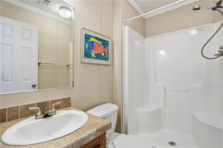 Bathroom with vanity, a stall shower, and ornamental molding