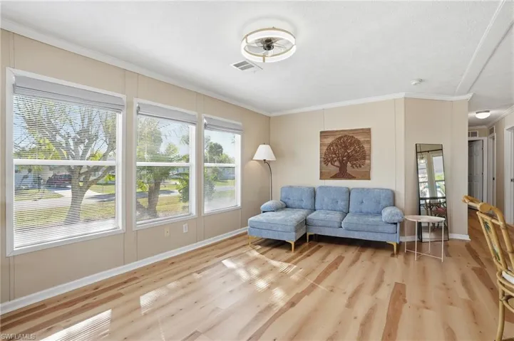 Living area featuring crown molding, plenty of natural light, and light wood-type flooring