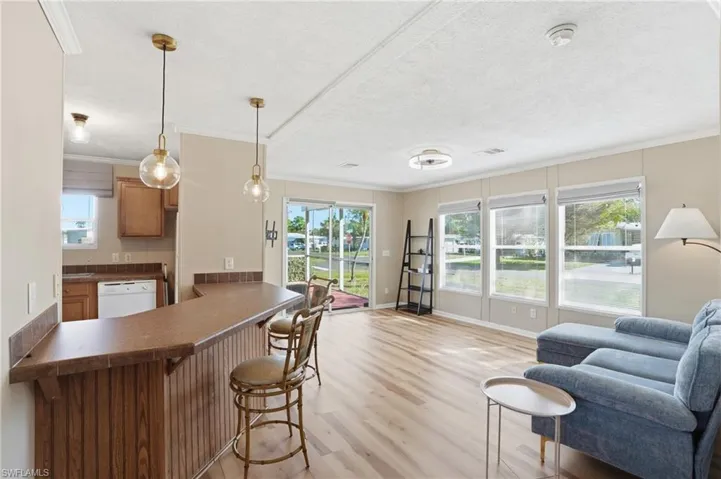 Kitchen featuring dark countertops, a breakfast bar area, a peninsula, hanging light fixtures, and light wood-style floors