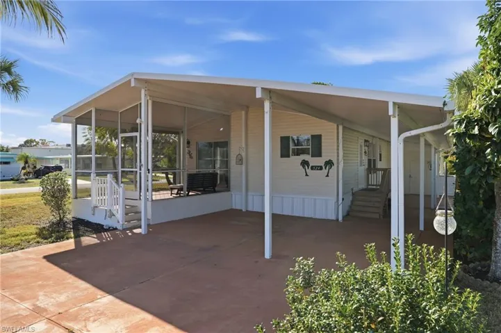 View of patio featuring a carport, a sunroom, concrete driveway, and entry steps