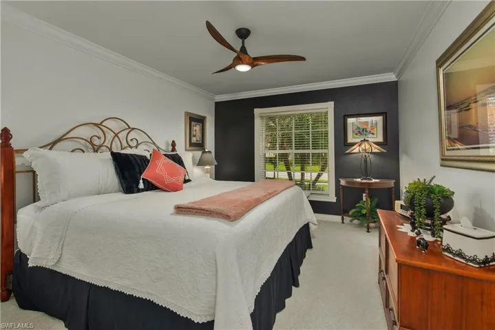 Bedroom with ornamental molding, light carpet, baseboards, and a ceiling fan