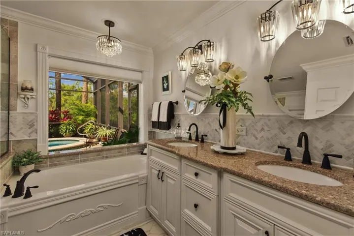 Full bath featuring a bath, an inviting chandelier, crown molding, and a sink