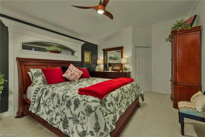 Bedroom featuring ceiling fan, lofted ceiling, light carpet, baseboards, and ornamental molding