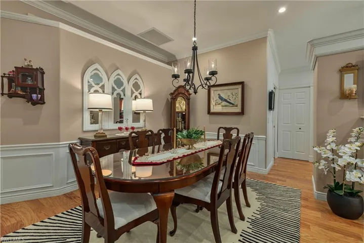 Dining space with light wood-type flooring, wainscoting, visible vents, and crown molding