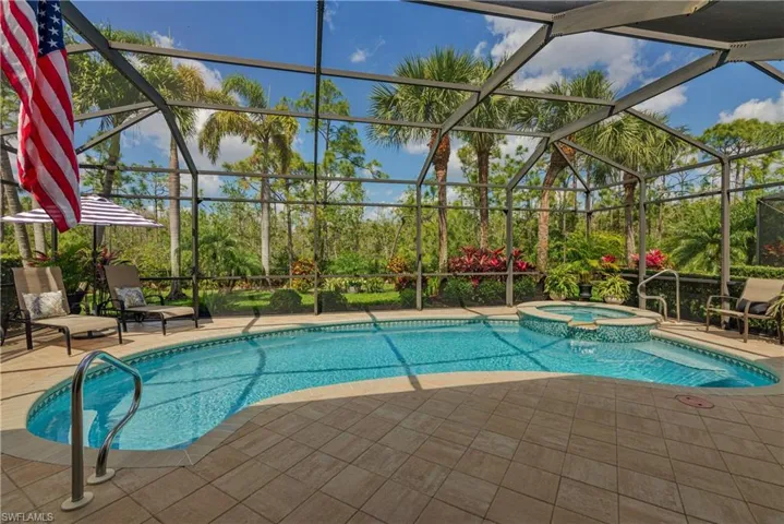 View of pool featuring a pool with connected hot tub, a patio area, and a lanai