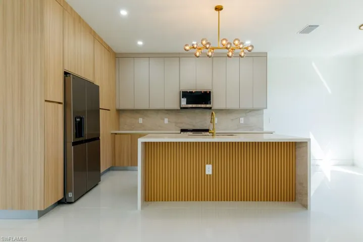 Kitchen featuring modern cabinets, backsplash, hanging light fixtures, stainless steel appliances, and recessed lighting