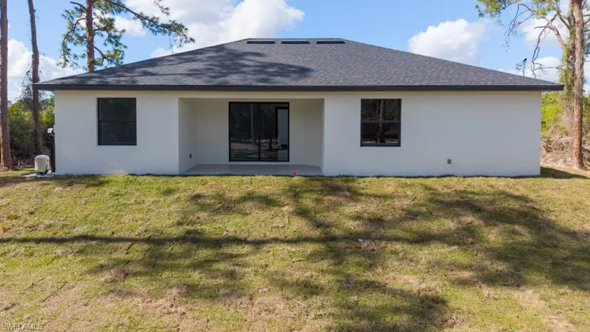 Rear view of property with a patio area, a yard, stucco siding, and roof with shingles