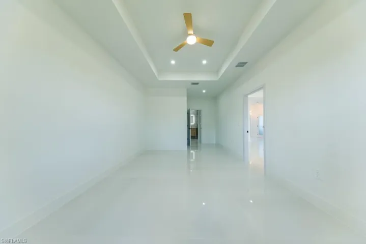 Unfurnished room with a raised ceiling, recessed lighting, and a ceiling fan
