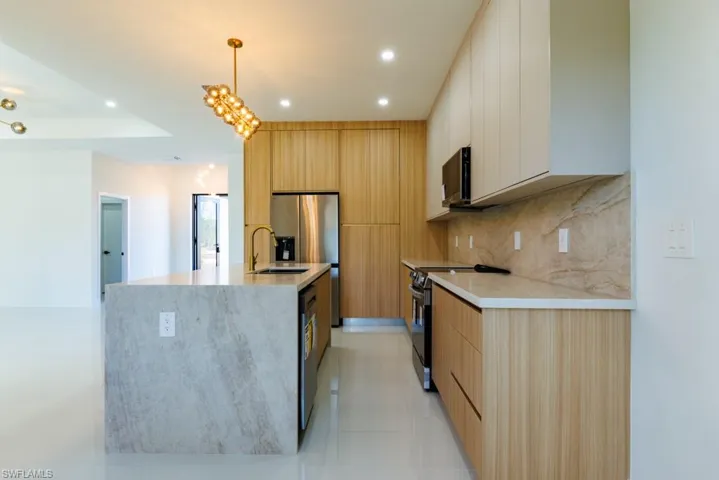 Kitchen featuring black appliances, modern cabinets, recessed lighting, backsplash, and decorative light fixtures