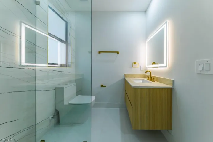 Bathroom featuring vanity, a marble finish shower, and light tile patterned floors