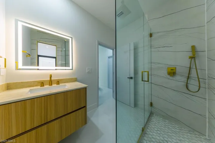 Full bath featuring a marble finish shower and vanity