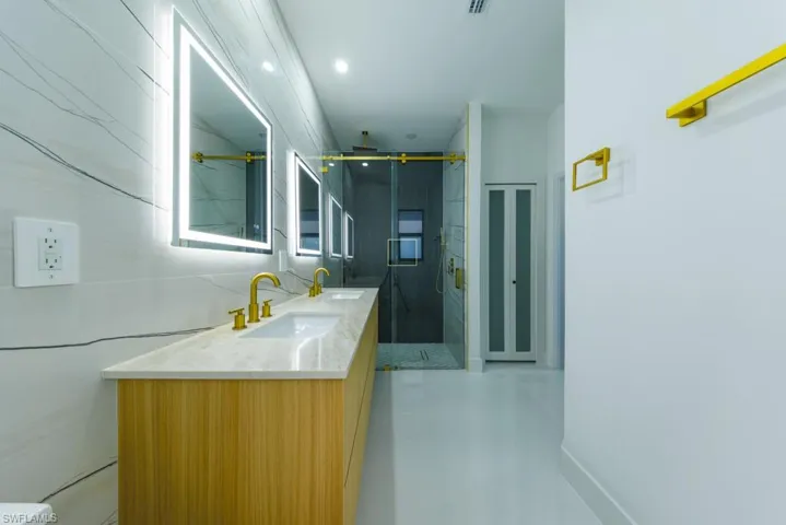 Bathroom featuring a marble finish shower, double vanity, and recessed lighting